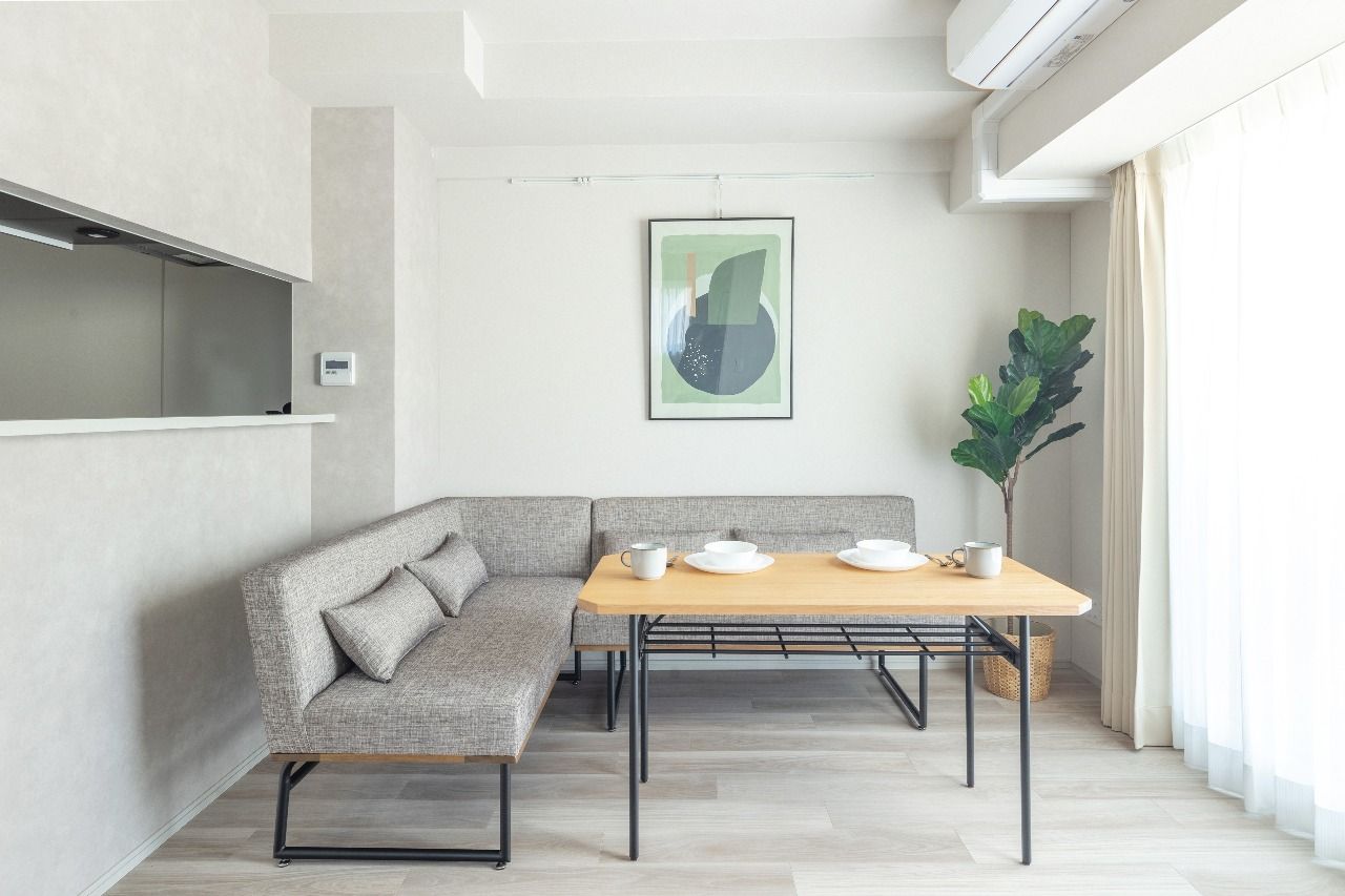 Modern dining area features a light wood table and gray L-shaped bench.