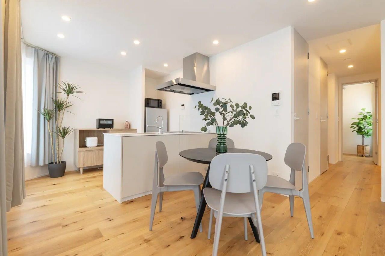 Modern open-plan living space featuring a kitchen island, dining table, and light wooden floors.