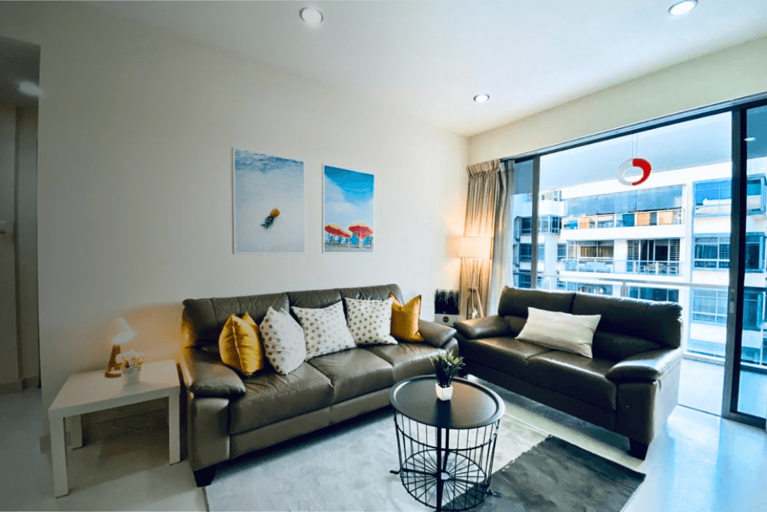 Modern living room with dark leather sofas, black coffee table, and large window overlooking city buildings.