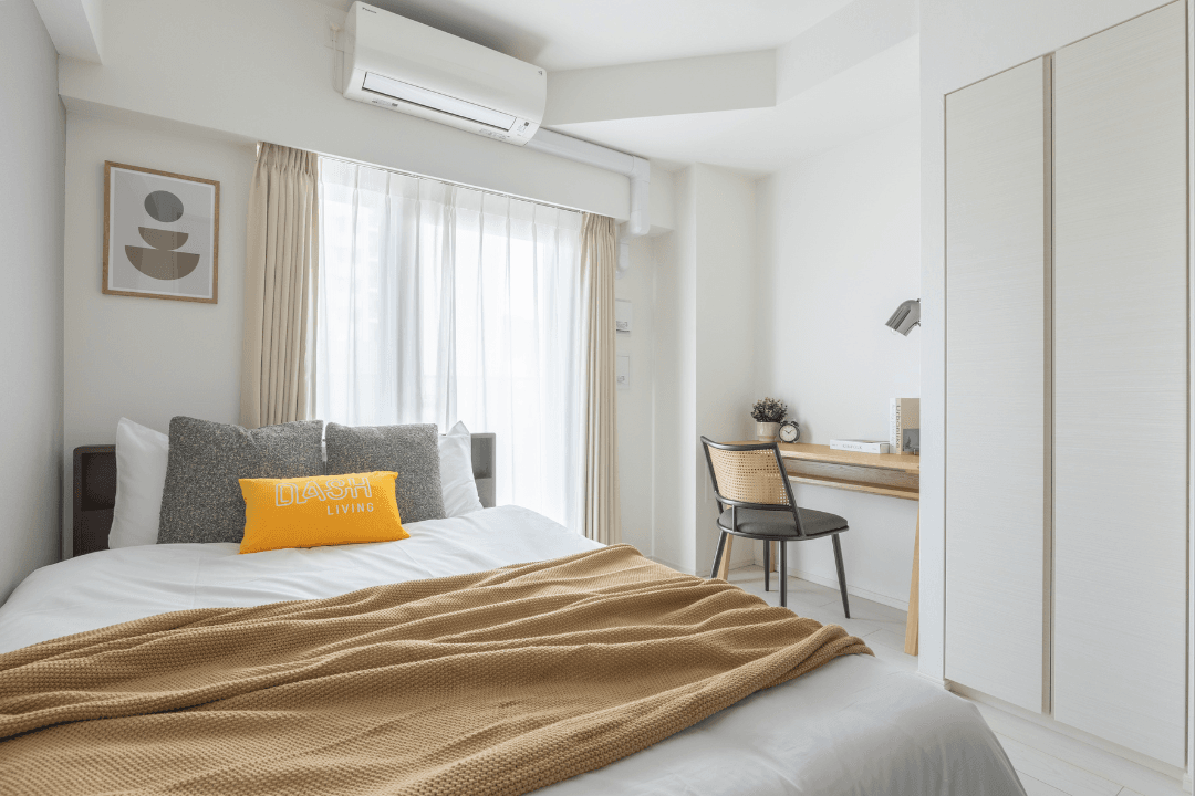 Modern small bedroom featuring a cozy bed, wooden desk, and minimalist white aesthetic.
