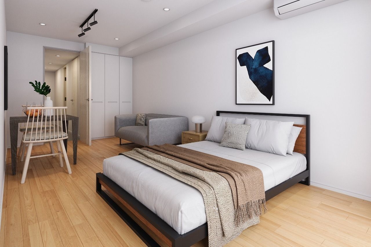 Bright modern studio apartment with a bed, dining table, and abstract wall art.