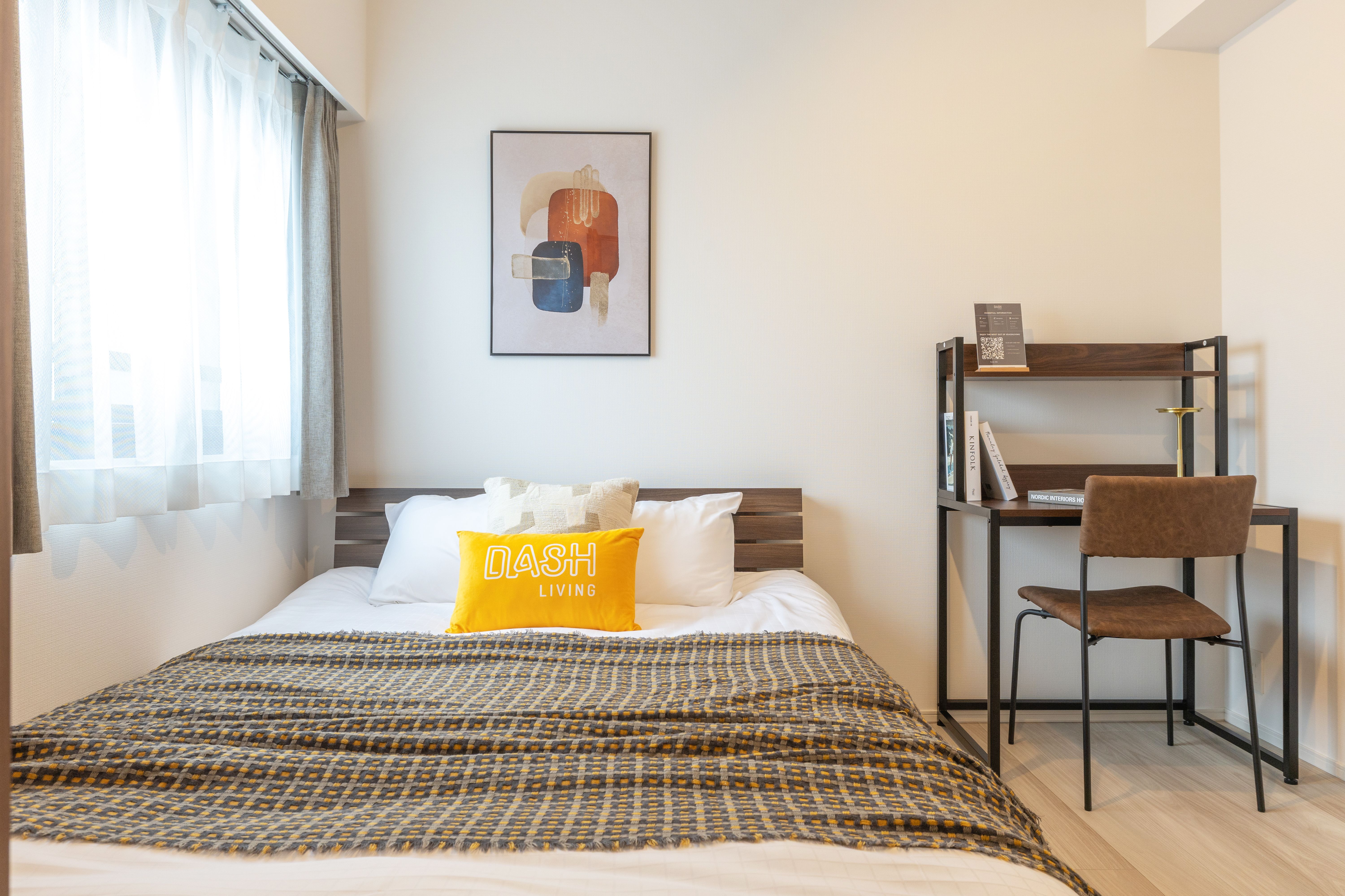 Modern minimalist bedroom with wooden bed, yellow pillow, window, and small desk setup.