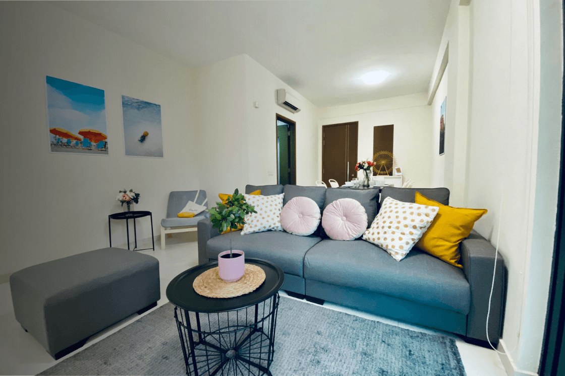 Modern living room with a grey sofa, colorful pillows, coffee table, and wall art.
