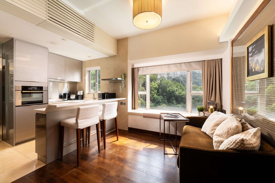 Modern studio apartment with bright kitchen, breakfast bar, sofa, and large window view.