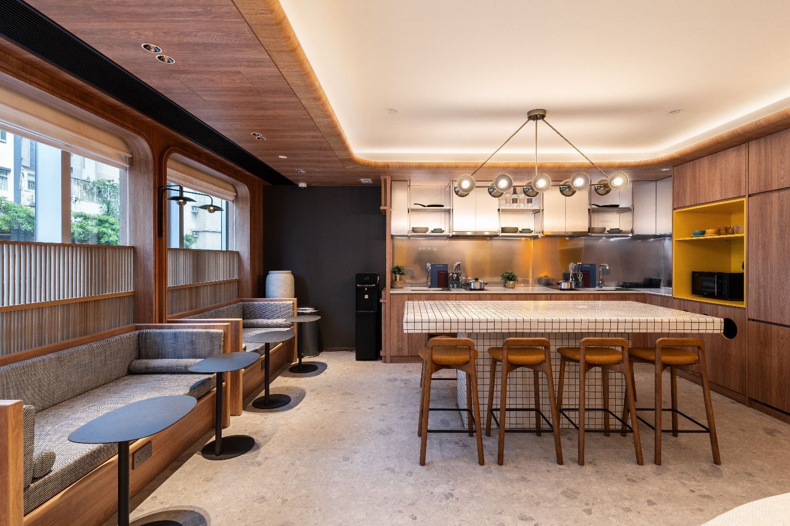 Modern office breakroom with a large kitchen island, bar stools, and booth seating.