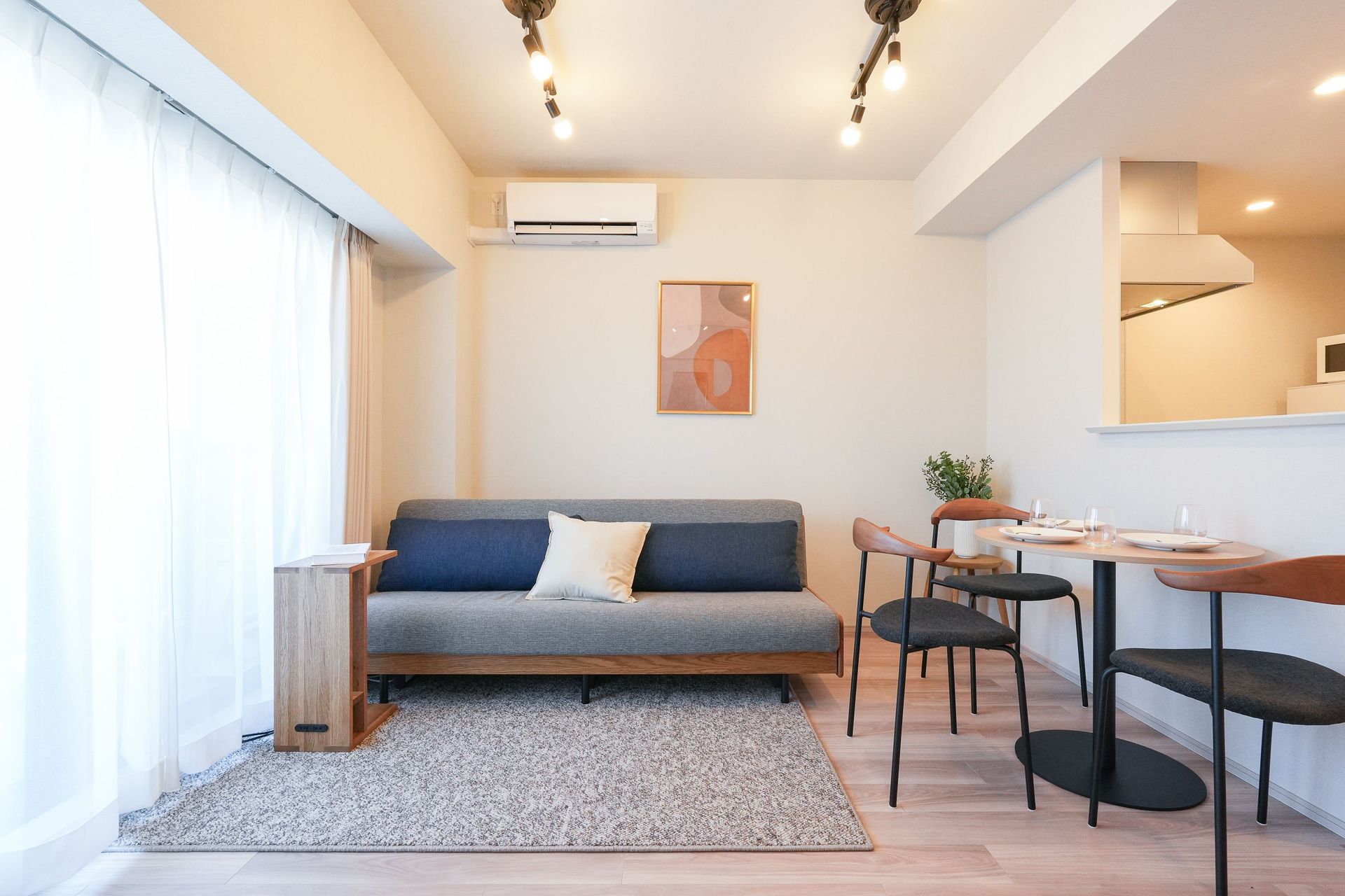 Modern living room with a gray sofa, wooden dining table, and minimalist decor.