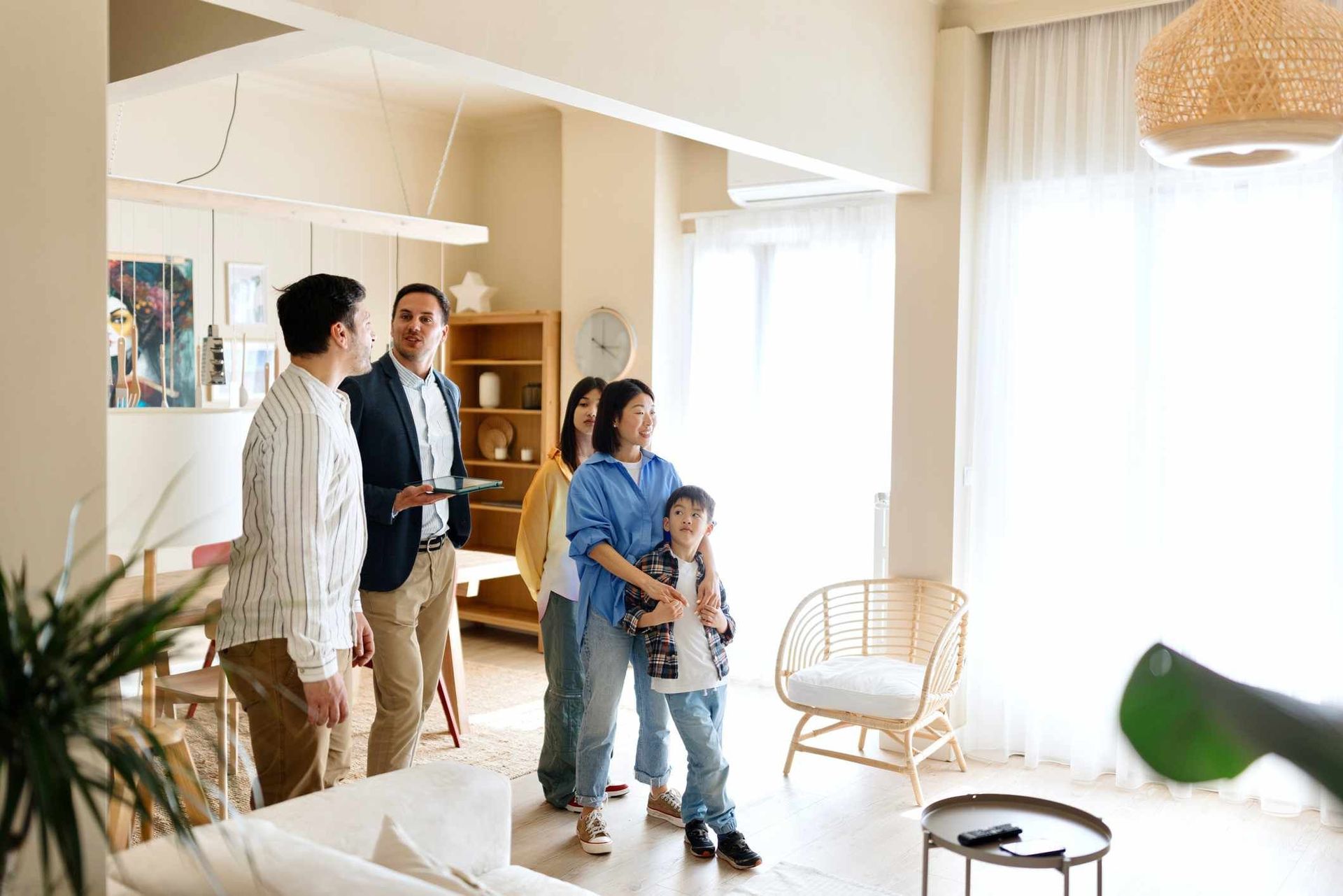 A realtor shows a family a bright, modern living room in a house for sale.